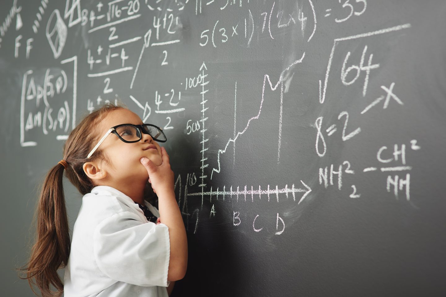 Little girl looking at mathematical equations on a board, transferable skill